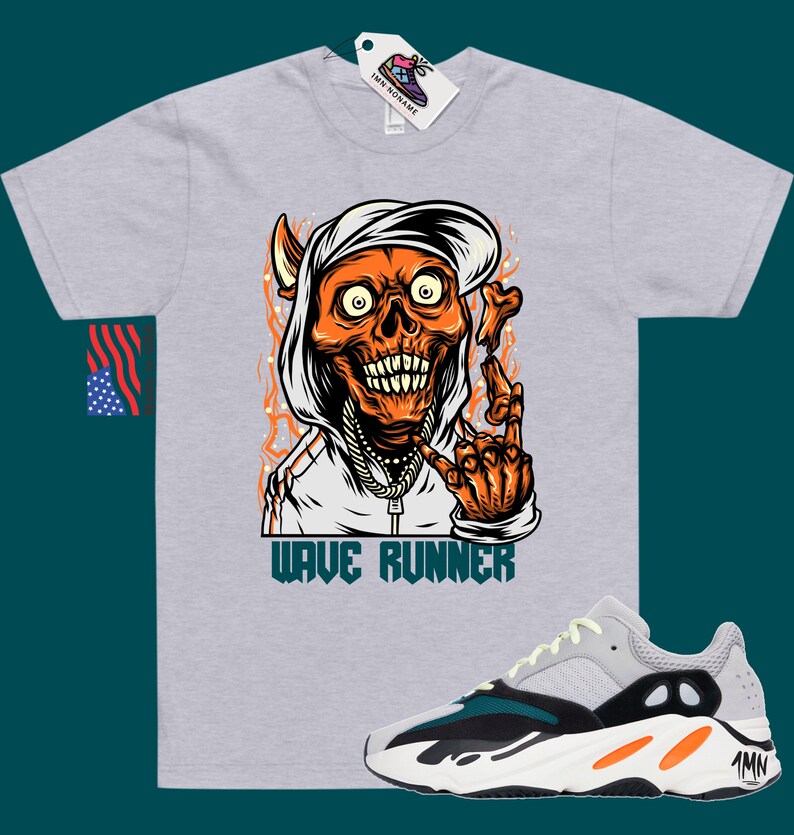 Puede incluir: Una camiseta gris con un gr&aacute;fico de una calavera con capucha y una cadena de oro. La calavera es naranja y tiene un cuerno de diablo. El texto "WAVE RUNNER" est&aacute; impreso debajo del gr&aacute;fico. Un par de zapatillas grises, negras y naranjas con el texto "Yeezy" en el lateral.