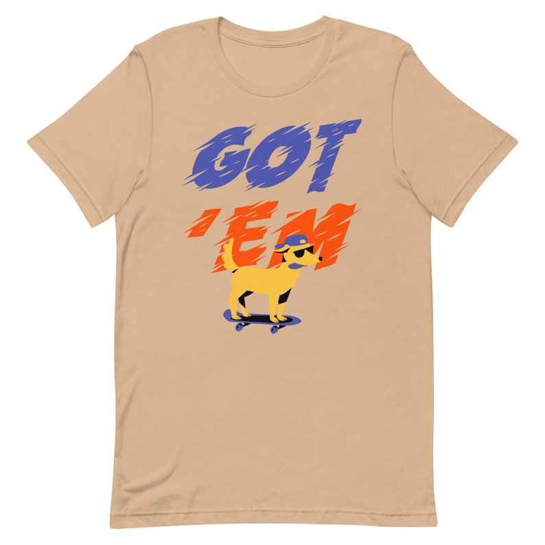 May include: A tan t-shirt with the text "GOT 'EM" in blue and orange letters. A yellow cartoon dog wearing sunglasses and a blue hat is skateboarding.
