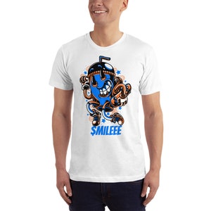May include: White t-shirt featuring a blue and orange cartoon character of a smiling cup with a straw. The character is wearing trainers and has a blue and orange hat. The text "$MILEEE" is printed below the character.