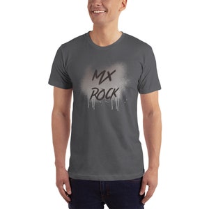 以下が含まれることがあります： 白いスプレーペイント効果と黒い「MX ROCK」の文字が入った濃いグレーのTシャツです。