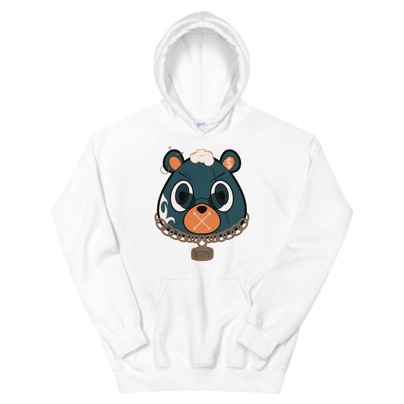 May include: White hooded sweatshirt featuring a cartoon bear face with teal, orange, and gold accents. The bear has a chain necklace and a pendant. The bear's eyes are large and round, and the mouth is an orange cross.