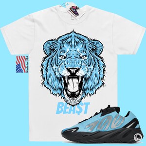 May include: White t-shirt with a blue lion graphic and the word "BEAST" printed below. A pair of blue and black sneakers with the number "700" printed on the side.