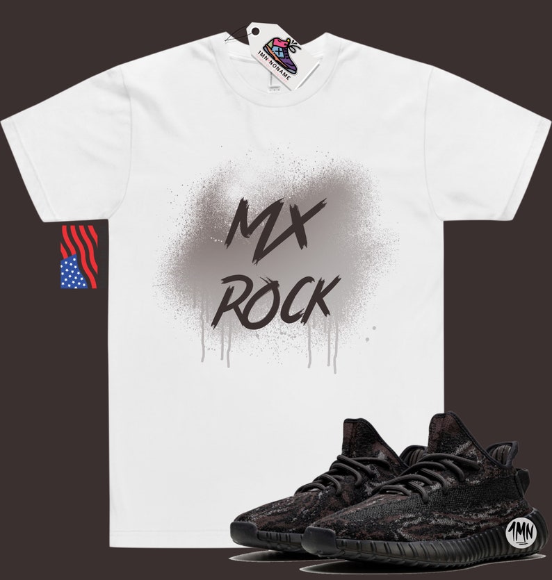 以下が含まれることがあります： 白いTシャツに、グレーのスプレーペイントで「MX ROCK」と書かれたデザインが施されています。黒と茶色の迷彩柄のスニーカーで、ソールは黒です。