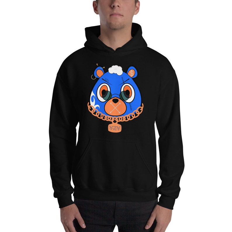 May include: Black hoodie with a blue and orange cartoon bear wearing a gold chain with a YZY pendant. The bear has a stitched mouth and a gold hoop earring.