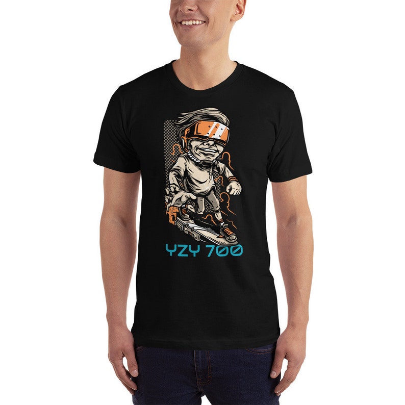 May include: Black t-shirt with a cartoon illustration of a person wearing a futuristic helmet and riding a skateboard. The text "YZY 700" is printed below the illustration.
