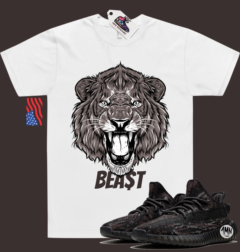 May include: White t-shirt with a black and white illustration of a lion's head and the word "BEAST" printed on the front. A pair of black and grey camouflage sneakers are shown below the shirt.