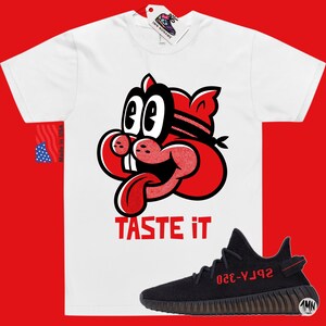 May include: White t-shirt with a red cartoon character with the text "TASTE IT" and a black and red Yeezy sneaker with the text "YZY-350" on the side.