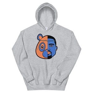May include: A gray hoodie with a graphic of a bear head and a man's face split in half. The bear is orange and the man's face is blue. The text "YZY" is on the man's forehead.