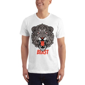 Puede incluir: Camiseta blanca con un gr&aacute;fico de una cabeza de le&oacute;n rugiente en negro y gris con una lengua roja. El texto "BEAST" est&aacute; impreso en rojo debajo de la cabeza del le&oacute;n.