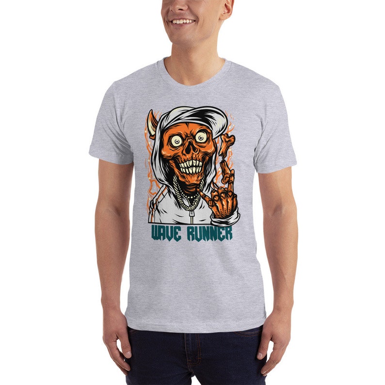 Puede incluir: Una camiseta gris con un gr&aacute;fico de una calavera con capucha haciendo un signo de paz. El texto "WAVE RUNNER" est&aacute; impreso debajo de la calavera.