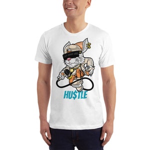 May include: White t-shirt with a cartoon rabbit wearing a hat, sunglasses, and a gold chain. The rabbit is holding a microphone and a spray can. The text "HUSTLE" is printed below the rabbit.