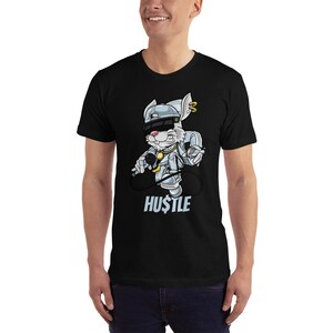 May include: Black t-shirt featuring a cartoon rabbit wearing a backwards baseball cap, sunglasses, and a gold chain. The rabbit is holding a microphone and a spray can. The text "HUSTLE" is printed below the rabbit.