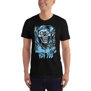 May include: Black t-shirt with a graphic of a blue skull wearing a blue hoodie and giving the middle finger. The text "424 700" is printed below the skull.