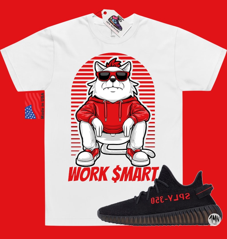 Puede incluir: Camiseta blanca con un gato de dibujos animados con gafas de sol y una sudadera roja. El gato est&aacute; sentado sobre un fondo a rayas rojo y blanco. El texto "WORK $MART" est&aacute; impreso debajo del gato. Un par de zapatillas Yeezy negras y rojas se muestran debajo de la camiseta.