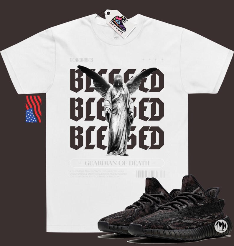 May include: White t-shirt with a black and white graphic of an angel with wings and the text "Blessed" repeated three times. The text "Guardian of Death" is below the graphic. A pair of black and brown sneakers are in the bottom right corner of the image.