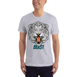 May include: A grey t-shirt featuring a white lion's head graphic and the word "BEAST" in teal lettering.