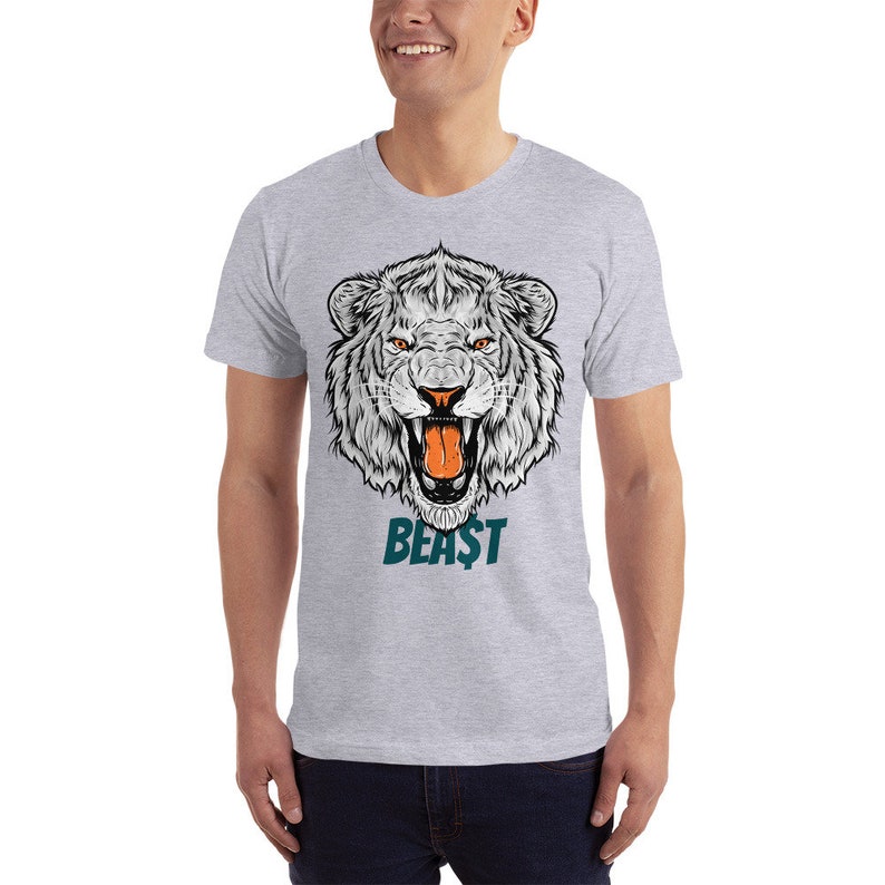 May include: A grey t-shirt featuring a white lion's head graphic and the word "BEAST" in teal lettering.