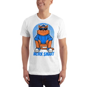 Op de afbeelding: Wit T-shirt met een cartoonkat die een zonnebril en een blauwe hoodie draagt. De kat zit met gekruiste benen en de tekst "WORK $MART" staat onder de kat.