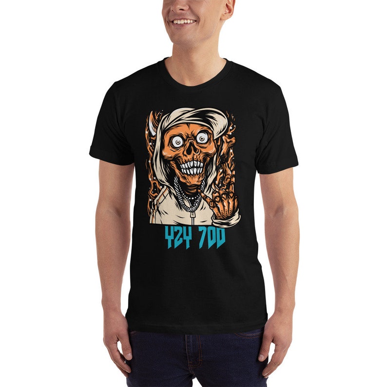 May include: Black t-shirt with a graphic of a cartoon skull wearing a white hoodie and making a peace sign. The text "424 700" is printed below the graphic.