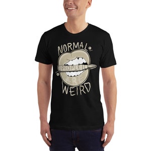 Pode incluir: Camiseta preta com um gr&aacute;fico de uma boca de desenho animado com um l&aacute;pis saindo. O l&aacute;pis diz "As pessoas s&atilde;o estranhas" e o texto acima da boca diz "Normal."