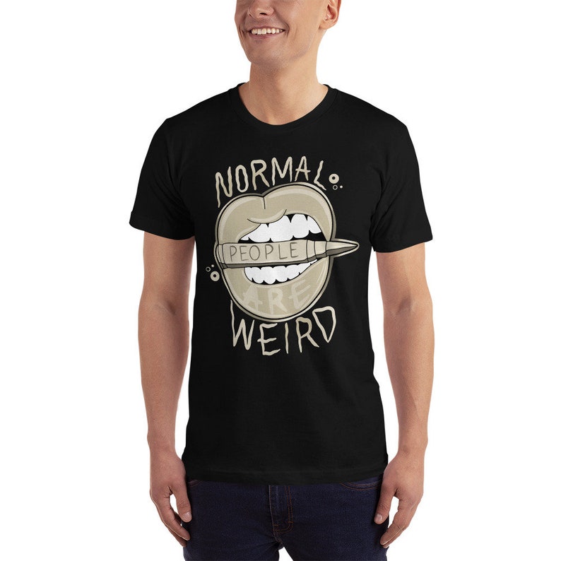 Pode incluir: Camiseta preta com um gr&aacute;fico de uma boca de desenho animado com um l&aacute;pis saindo. O l&aacute;pis diz "As pessoas s&atilde;o estranhas" e o texto acima da boca diz "Normal."