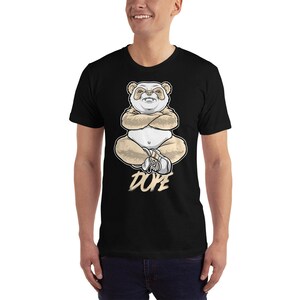 May include: Black t-shirt with a graphic of a cartoon panda sitting with its arms crossed and the word "DOPE" printed below.