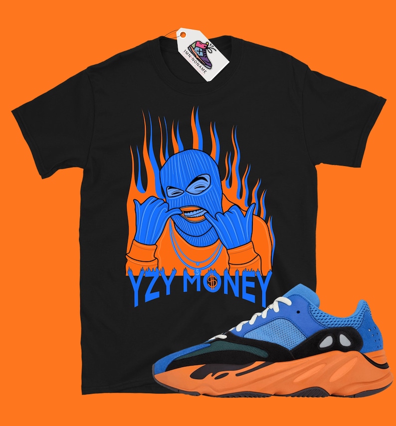 May include: Black t-shirt with a blue masked figure with orange flames and the text "YZY MONEY".  A pair of blue and orange sneakers are also pictured.