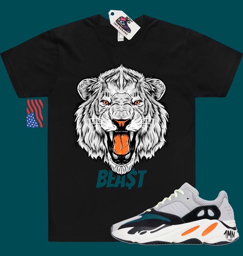 May include: Black t-shirt featuring a white lion graphic and the word "BEAST" in teal. The t-shirt is paired with white, grey, black and orange trainers with the text "Yeezy" on the side.