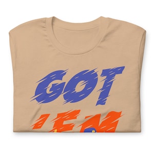 May include: A tan t-shirt with the words "GOT 'EM" printed in blue and orange.