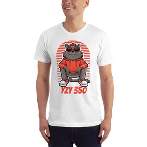 Pode incluir: Camiseta branca com uma ilustra&ccedil;&atilde;o de desenho animado de um gato usando &oacute;culos de sol vermelhos, um moletom vermelho e t&ecirc;nis brancos. O gato est&aacute; sentado com as pernas cruzadas e o texto "YZY 350" est&aacute; impresso abaixo do gato.