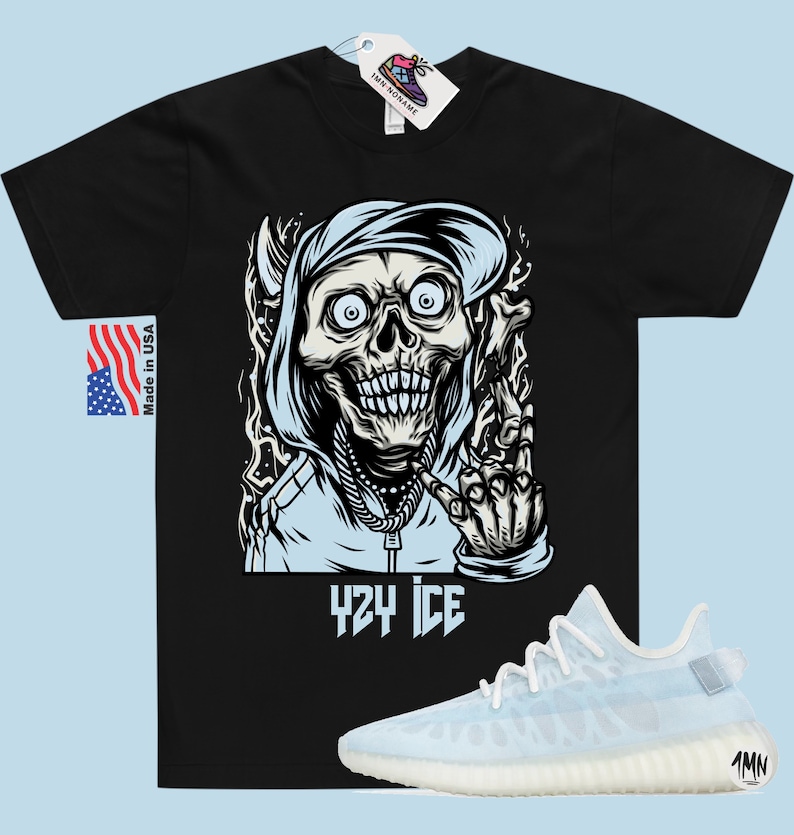 May include: Black t-shirt with a graphic of a skull wearing a blue hoodie and making a hand gesture. The text "424 ICE" is below the graphic. A pair of light blue and white sneakers are shown below the t-shirt.