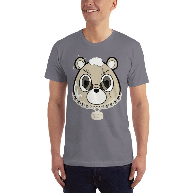 May include: A gray t-shirt with a cartoon bear wearing a chain with a pendant that says "WAVY 1ST". The bear has a stitched-up face and is wearing a pair of sunglasses.