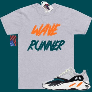 May include: A grey t-shirt with the words "Wave Runner" printed in orange and green. A pair of white, black, green, and orange sneakers are shown below the t-shirt.