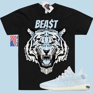 K&ouml;nnte beinhalten: Schwarzes T-Shirt mit einem wei&szlig;en Tiger-Motiv und dem Wort "BEAST" in wei&szlig;en Buchstaben. Das T-Shirt wird mit hellblauen Sneakern mit wei&szlig;er Sohle kombiniert.