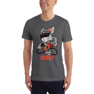 May include: A dark gray t-shirt with a cartoon rabbit wearing a red hat, sunglasses, and a gold chain. The rabbit is holding a microphone and a dollar bill. The text "HUSTLE" is printed below the rabbit in red.