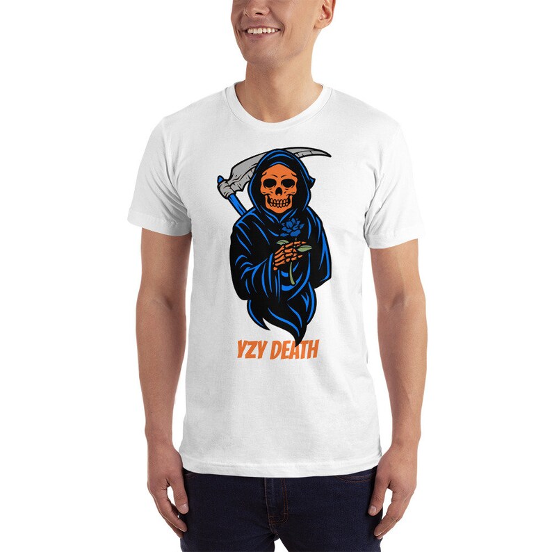 May include: White t-shirt with a graphic of the Grim Reaper, holding a scythe and a blue rose. The Reaper has an orange skull and wears a black robe with blue accents. The text "YZY DEATH" is printed in orange below the graphic.