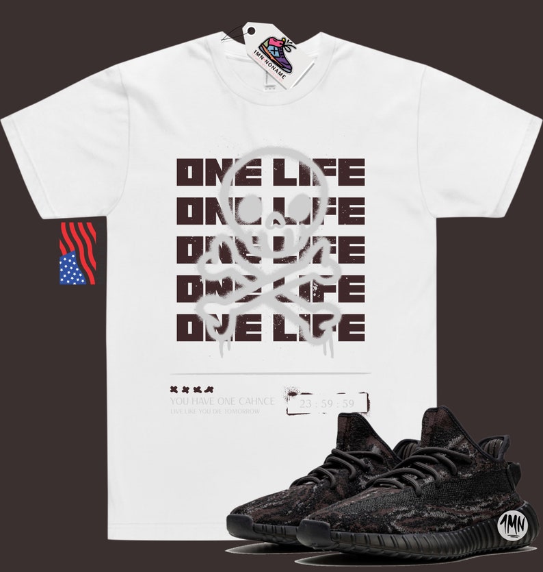 May include: White t-shirt with a black and white skull and crossbones graphic and the text "ONE LIFE" repeated five times. The text is in a graffiti style font. A pair of black and brown sneakers are also pictured.