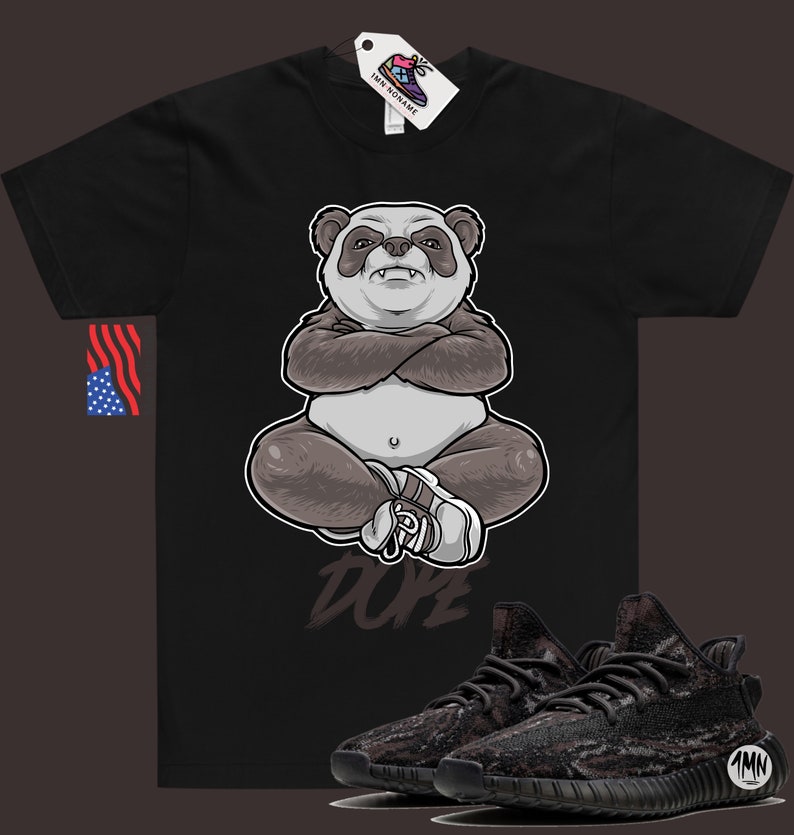 Peut inclure: T-shirt noir avec un panda dessin anim&eacute; portant un chapeau blanc et assis en tailleur. Le panda porte une chemise blanche et a un cache-&oelig;il noir. Le texte "Dope" est imprim&eacute; sous le panda. Une paire de baskets noires et grises est repr&eacute;sent&eacute;e sous le t-shirt.