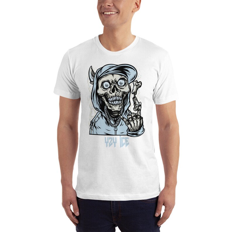 May include: White t-shirt with a graphic of a cartoon skull wearing a blue hoodie and a backwards baseball cap. The skull is giving the middle finger and has the text "424 ICE" below it.