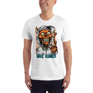 Puede incluir: Camiseta blanca con un gr&aacute;fico de una calavera con una sudadera con capucha y una cadena. La calavera es naranja y tiene una sonrisa diab&oacute;lica. El texto "WAVE RUNNER" est&aacute; impreso debajo de la calavera.