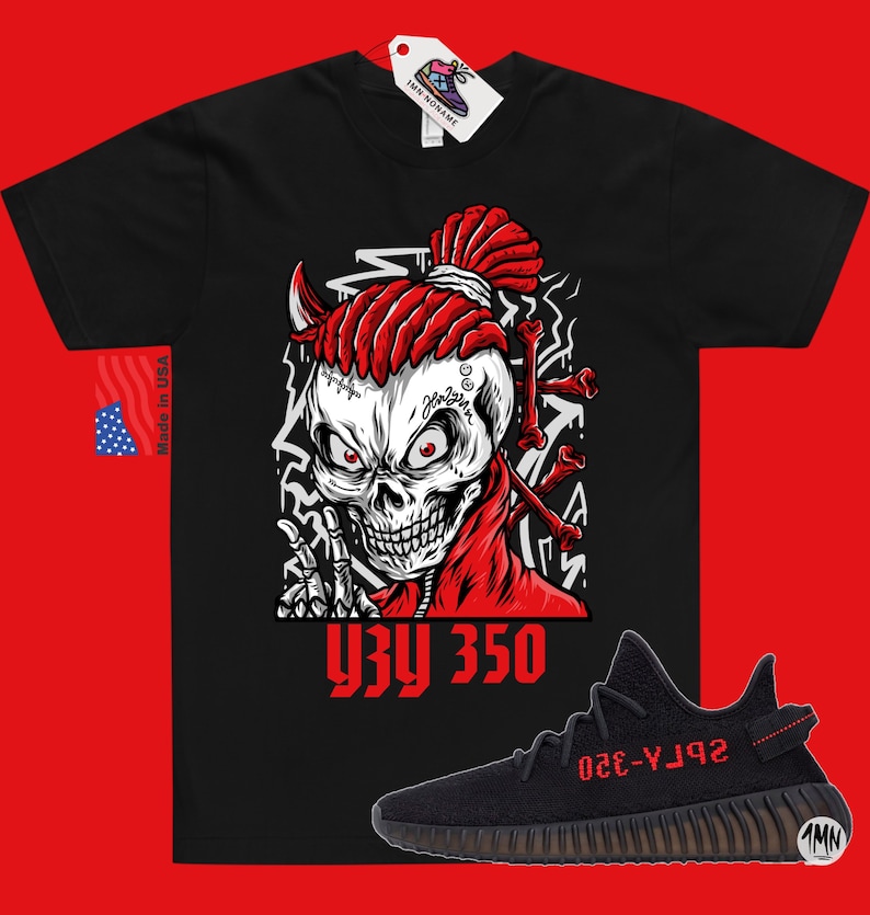 Op de afbeelding: Zwart T-shirt met een rode schedelprint en de tekst "YZY 350". Onder het T-shirt is een paar zwarte en rode Yeezy 350 sneakers te zien.