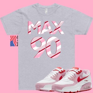 May include: Gray t-shirt with the words "MAX 90" in pink and red stripes.  Pink and white sneakers with red accents and a white Nike swoosh.