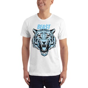以下が含まれることがあります： 青い文字で「BEAST」と書かれた、青と白の虎のグラフィックがプリントされた白いTシャツです。
