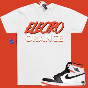 May include: White t-shirt with the text "Electro Orange" in red and white. A pair of black and white high-top trainers with orange accents.