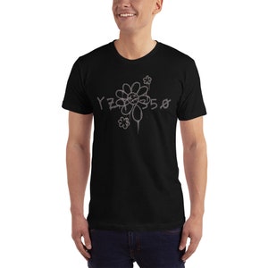 Pode incluir: Camiseta preta com um gr&aacute;fico cinza de uma flor estilizada com o texto "YZY 5.0" nela.