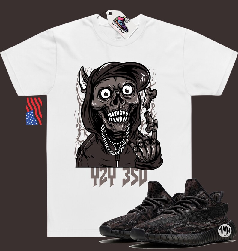 Puede incluir: Camiseta blanca con un gr&aacute;fico de una calavera con capucha y una cadena, con el texto "424 350" debajo. Tambi&eacute;n se muestra un par de zapatillas de deporte de camuflaje negro y marr&oacute;n.