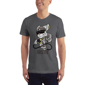 May include: A dark gray t-shirt with a cartoon rabbit wearing a backwards baseball cap, sunglasses, and a gold chain. The rabbit is holding a microphone and a spray can. The text "HUSTLE" is printed below the rabbit.