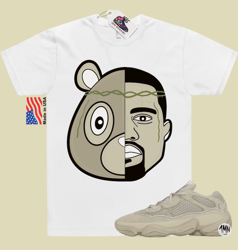 May include: White t-shirt with a graphic of a bear and Kanye West's face. The graphic is split down the middle, with the bear on the left and Kanye on the right. The bear is wearing a crown of thorns.  A pair of beige sneakers with a mesh upper and a thick sole are shown below the t-shirt.