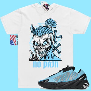 May include: White t-shirt with a blue skull graphic and the text "no pain".  A pair of blue and black sneakers with the number "700" on the side.