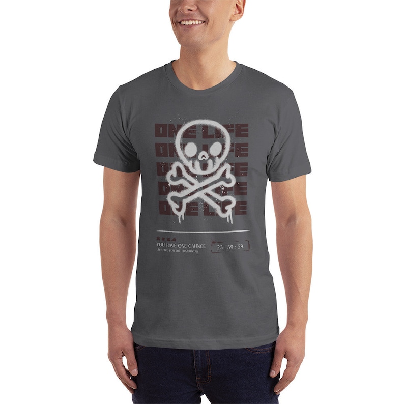 May include: A dark gray t-shirt with a white skull and crossbones graphic. The graphic is surrounded by the words "ONE LIFE" in a maroon color. The text "YOU HAVE ONE CHANCE" and "23:59:59" are printed below the graphic.